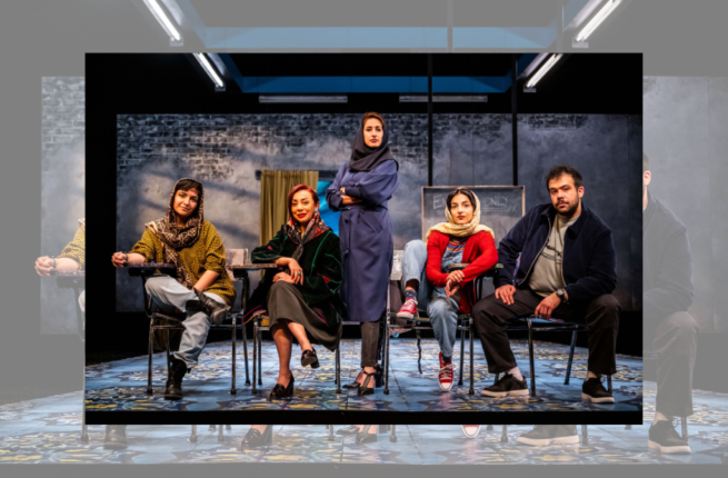 The banner image for Intermission Magazine's review of English. The photo features the cast of English, lined up onstage. Four of the individuals sit at school desks, gazing at the camera: some smile, others look inquisitive. The man wears a dark jacket and trousers, while the women wear brighter colours and patterned hijabs. A woman in blue with a dark hijab stands in the centre of the line, her arms crossed, staring intently into the camera with a gentle smile.
