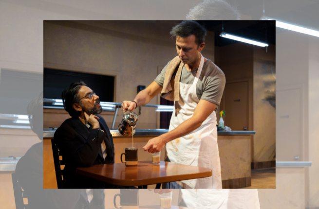 Man in apron pours coffee into cup on table that another man in black sits at, in a restaurant setting.