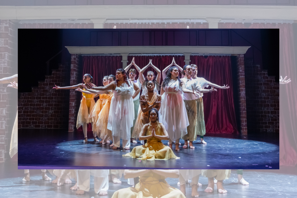 12 cast members on stage wearing flowy dresses and pants in whites, oranges, and greens. Hands spread out or together about their heads.