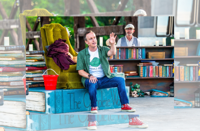 Jeremy Smith sits atop a massive volume of Shakespeare's completed works. He wears a yoda t-shirt with a green button-down, jeans, and red Converse sneakers. His arm is raised as though speaking dramtically. Around him is a cluttered stage: books, figurines, a chartreuse velvet "throne," and a red plastic pail surround him. Behind him, Tom Lillington is just visible behind a piano. Original image by Dahlia Katz.