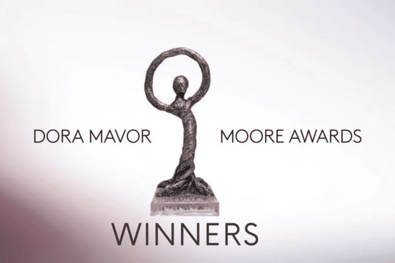 An image of a Dora Mavor Moore Award on a white background. The statue displays a bronze humanoid figure, its arms raised above its head to create a circle. Surrounding the statue is text reading 