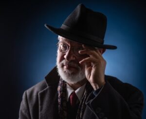 Photo of a white man in a dark suit and hat. Diego Matamoros by Dahlia Katz.