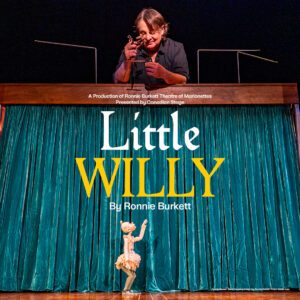 A puppet is standing on stage and looking upwards towards the title of the show - Little Willy