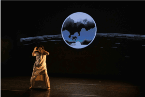 women standing in front of circle on stage with her arms out