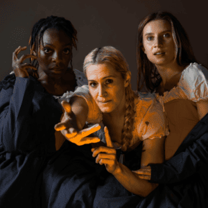 Dawn Jani Birley, Nickeshia Garrick, and Juliana Monk posed in front of a grey backdrop with warm lighting.